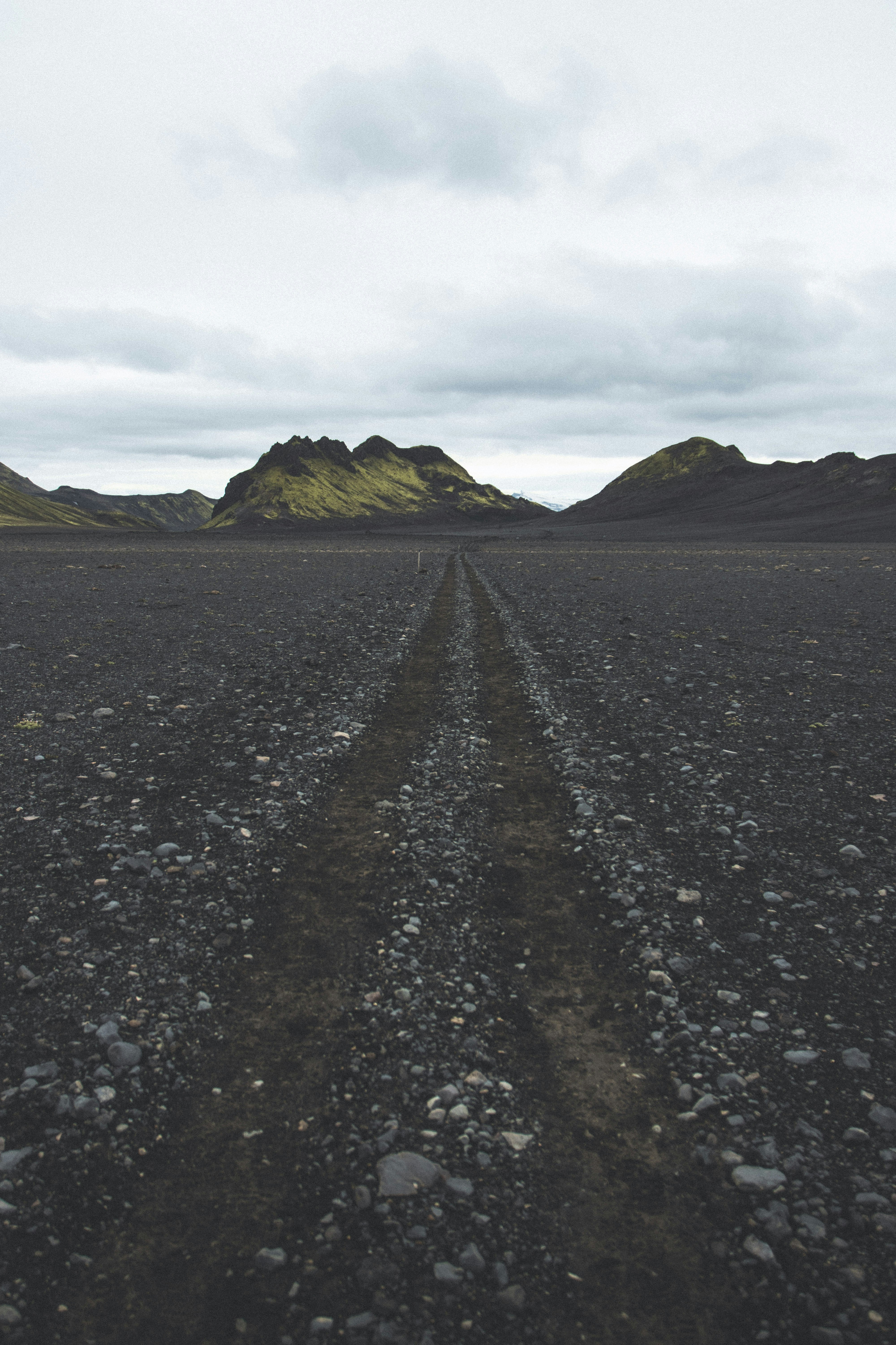 gray road between green grass field during daytime